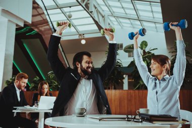 Kurumsal spor yaşam tarzı. Sağlık iş adamları. Ofis çalışanları dumbell ile çalışma. İşçiler Fitness egzersizleri yapıyor. Yoga pratik. Gülümseyen için sağlıklı kadın çalışan adam.