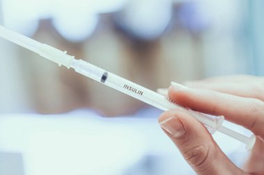 Eczacı insülin şırıngayla elinde tutuyor. Genç kadın eczacı. İnsülin şeker hastalığı için bir ilaçtır. Eczanede bulunan kadın. El şırıngada closeup görünümü.