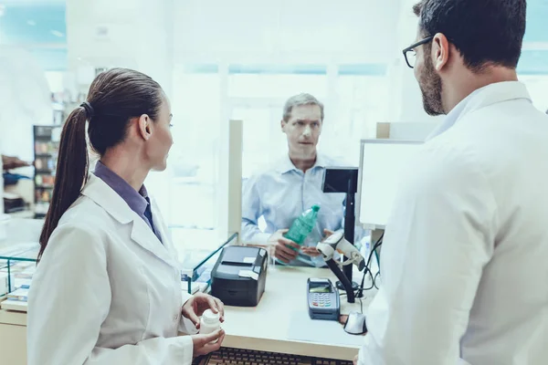 Farmacéuticos Trabajando Counter Hombre Compra Agua Mineral Farmacéutica Femenina Sosteniendo — Foto de Stock