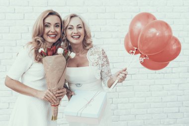 Hediye kutusu ve buket beyaz elbiseli kadın. Genç kadın. Kırmızı balon. Uzun saçlı. Ayakta kadın. Kırmızı lale. Beyaz çiçek. Kutlama kavramı. Mart ayında tatil. Buket elinde tutan.