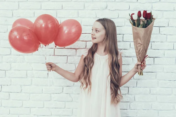 花束と風船の部屋に立っている少女 若い女の子 赤い風船 髪は長い 白いドレス 赤いチューリップ 白い花 お祝いのコンセプトです 花束を手に保持しています チューリップの花束 — ストック写真