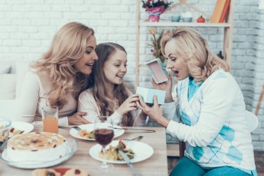 Aile evde büyük annemin Doğum günü kutluyor. Pasta masada. Mutlu bir aile. Anne ile kızı. Gülümseyen kadın. Gülümseyen büyükanne. Kutlama kavramı. Bir bardak şarap. Veren hediye kutusu.