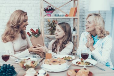 Aile evde annesinin Doğum günü kutluyor. Pasta masada. Mutlu bir aile. Anne ile kızı. Gülümseyen kadın. Gülümseyen büyükanne. Kutlama kavramı. Bir bardak şarap. Lale buketi.