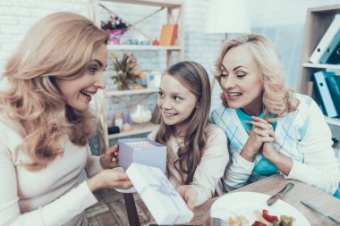Aile evde annesinin Doğum günü kutluyor. Pasta masada. Mutlu bir aile. Anne ile kızı. Gülümseyen kadın. Gülümseyen büyükanne. Kutlama kavramı. Bir bardak şarap. Veren hediye kutusu.