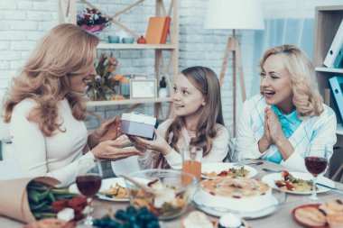 Aile evde annesinin Doğum günü kutluyor. Pasta masada. Mutlu bir aile. Anne ile kızı. Gülümseyen kadın. Gülümseyen büyükanne. Kutlama kavramı. Bir bardak şarap. Veren hediye kutusu.