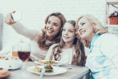 Kutluyor ve Selfie evde alarak mutlu bir aile. Pasta masada. Mutlu bir aile. Anne ile kızı. Gülümseyen kadın. Gülümseyen büyükanne. Kutlama kavramı. Smartphone kullanarak. Fotoğraf çekme.