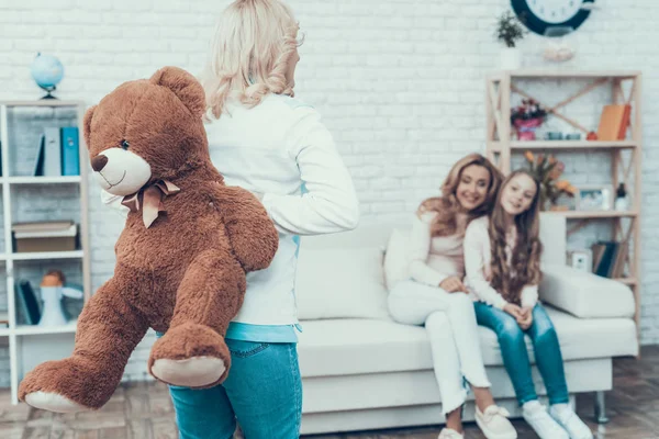 妈妈呈现玩具熊微笑的女儿 生日礼物 母亲与女儿 微笑的女人 坐在沙发上 庆祝理念 幸福的家庭 坐在家里 3月的假期 — 图库照片