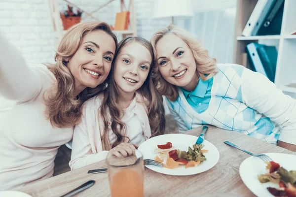 Kutluyor ve Selfie evde alarak mutlu bir aile. Pasta masada. Mutlu bir aile. Anne ile kızı. Gülümseyen kadın. Gülümseyen büyükanne. Kutlama kavramı. Smartphone kullanarak. Fotoğraf çekme.