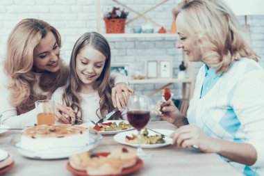 Mutlu aile kutluyor Doğum günü evde oturan. Pasta masada. Mutlu bir aile. Anne ile kızı. Gülümseyen kadın. Gülümseyen büyükanne. Kutlama kavramı. Bir bardak şarap. Meyve plaka üzerinde.