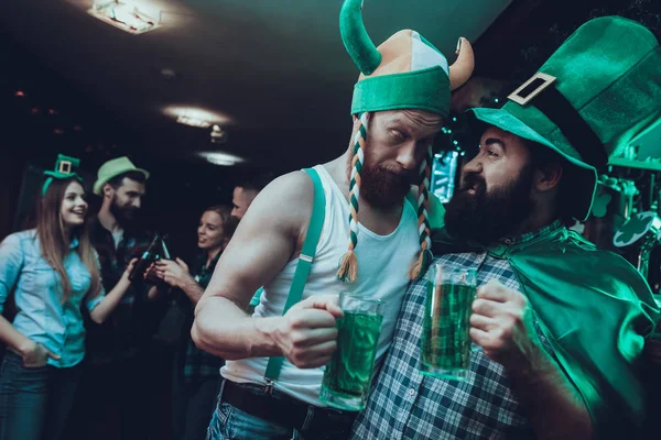 Saint Patrick's Day Party. Group of Friends is Celebrating. People is Drinking a Green Beer. Friends is Young Men and Women. Drunk Men Toast with Each Other. People Wearing a Green Hats. Pub Interior.