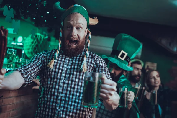 Saint Patrick\'s Day Party. Group of Friends is Celebrating. People is Drinking a Green Beer. Friends is Young Men and Women. People Wearing a Green Hats. Screaming Man Drinking a Beer. Pub Interior.