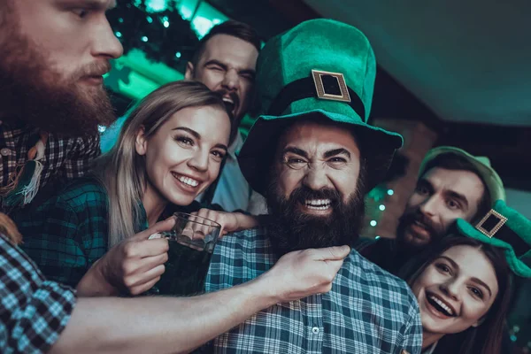 圣帕特里克节派对朋友们在庆祝 快乐的人是喝绿色啤酒 朋友是年轻的男人和女人 人在摸朋友的胡子 戴绿帽子的人 室内酒吧 — 图库照片