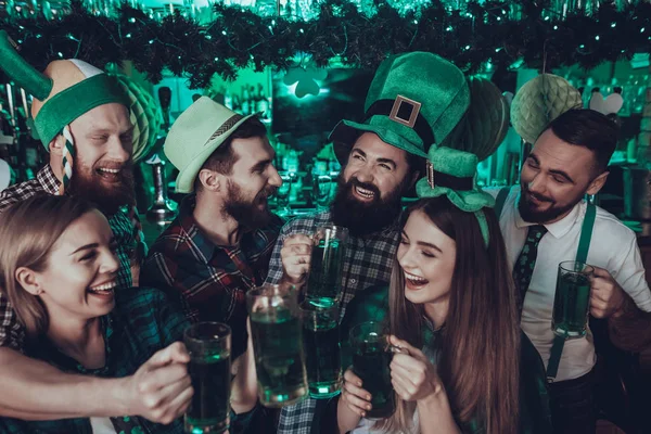 Saint Patrick\'s Day Party. Group of Friends and Barman is Celebrating. Happy People is Toast and Drinking a Green Beer. Friends is Young Men and Women. People Wearing a Green Hats. Pub Interior.