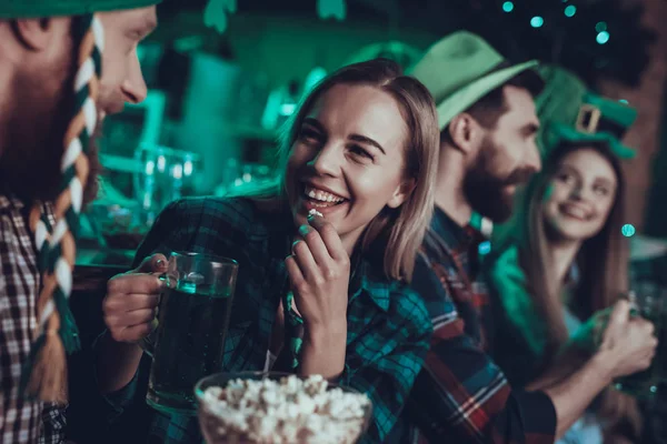 Saint Patrick\'s Day Party. Group of Friends is Celebrating. Happy People is Drinking a Green Beer and Eating a Popcorn. Friends is Young Men and Women. People Wearing a Green Hats. Pub Interior.