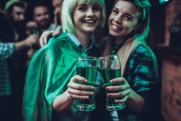 Saint Patrick\'s Day Party. Group of Friends is Celebrating. Happy People is Drinks a Green Beer. Friends is Young Men and Women. Women Toast with Each Other. People Wearing a Green Hats. Pub Interior.