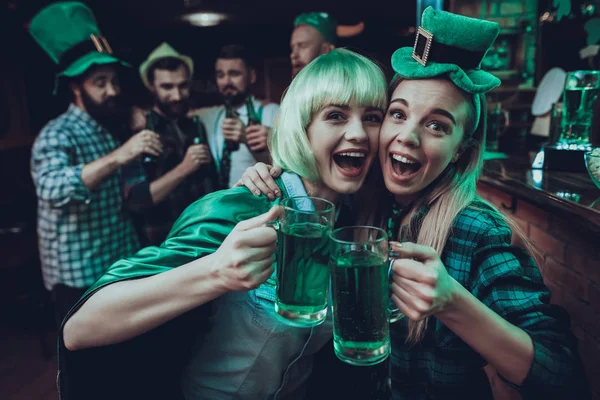 Saint Patrick\'s Day Party. Group of Friends is Celebrating. Happy People is Drinks a Green Beer. Friends is Young Men and Women. Women Toast with Each Other. People Wearing a Green Hats. Pub Interior.