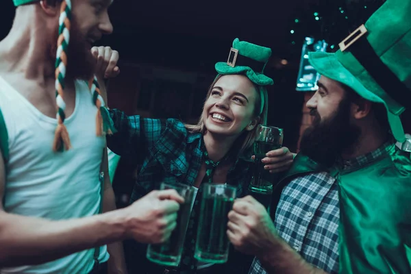 Saint Patrick\'s Day Party. Group of Friends is Celebrating. People is Drinking a Green Beer. Friends is Young Men and Woman. Happy Men Toast with Each Other. People Wearing a Green Hats. Pub Interior.