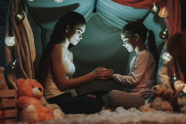 母女俩躺在地毯上 人们躺在假帐篷下 母亲和女儿手里拿着一盏明灯 人们都在微笑 晚上的时间 家庭内部的人 — 图库照片