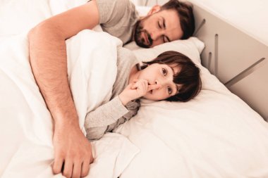 Yatakta yorgun uyuyan babası ile küçük oğlu. Sabah ailesinden. Mutlu aile kavramı. Beyaz yatak odasında. Baba ve oğul evde. Sabah rutin. Yatakta yatan. Uyuyan adam battaniye ve yastıklar.