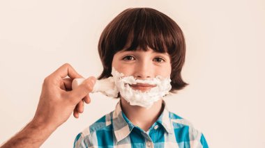 Genç baba küçük oğlu evde tıraş olmayı öğretir. Köpük yüzünde. Tıraş aracı. Razor ile Blade. Mutlu aile kavramı. Genç çocuk gömlek. Hijyen ve cilt bakımı kavramları. Hijyenik sabun.