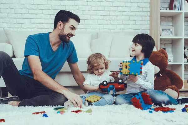 人把时间花在他的儿子身上 父亲正在抚养孩子 父子们在玩玩具 玩具是乐高和玩具车 人们坐在地毯上 人们位于卧室里 — 图库照片