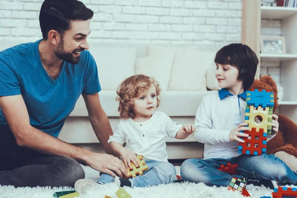 彼の息子との時間を費やしています 父親は子育てに取り組んでいます 父と息子は おもちゃで遊んでいます おもちゃがレゴです 人はカーペットの上に座っています 寝室にあります — ストック写真