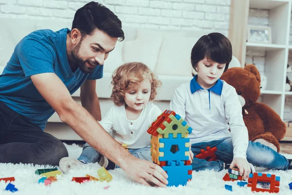 彼の息子との時間を費やしています 父親は子育てに取り組んでいます 父と息子は おもちゃで遊んでいます おもちゃがレゴです 人はカーペットの上に座っています 寝室にあります — ストック写真