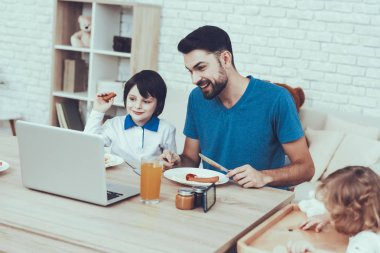 Oğulları ile zaman geçirir. Baba çocuk yetiştirme devreye girer. En büyük oğul ve baba 's Eating bir kahvaltı ve tarassut Video üstünde Laptop. İnsanlar masada oturuyor. Evde bulunan insanlar.