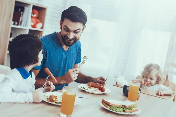 彼の息子との時間を費やしています 男の子のお父さんは 子育てに取り組んでいます 長男の息子と父親は 朝食を食べると笑顔です テーブルに座っています キッチンにある人々 — ストック写真