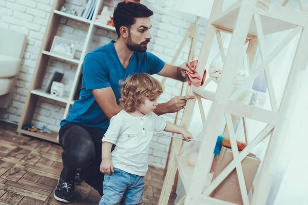 Man Spends Time with His Son. Father of Boy is Engaged in Raising Child. Father is Teaching a Son a Cleaning. Father and Son Wipe the Furniture Surfaces from Dust. People is Located in Bedroom.