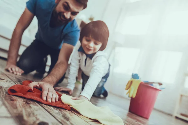 Man Spends Time with His Son. Father is Engaged in Raising Child. Father is Teaching a Son a Cleaning. Father and Son Washing the Floor with Rags. Persons is Smiling. People is Located in Bedroom.