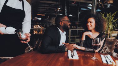 Şarap cam çift restoranda dökülen garson. Aşk dating romantik çift Afro-Amerikan. Neşeli erkek ve kadın kırmızı şarap içme. Romantik kavramı. Yıldönümü. Kırmızı şarap şişe.