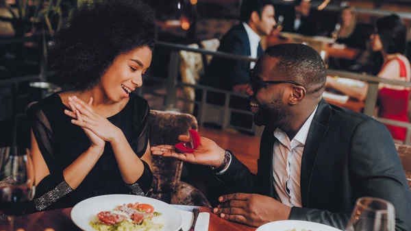 Kız arkadaşıma evlenme teklif Afrika yakışıklı adam. Aşk dating romantik çift. En adam ve kız bir restoranda. Romantik kavramı. Bir evlenme teklifi almak çekici kadın şaşırttı.