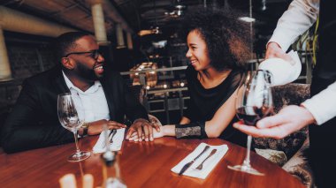 Şarap cam çift restoranda dökülen garson. Aşk dating romantik çift Afro-Amerikan. Neşeli erkek ve kadın kırmızı şarap içme. Romantik kavramı. Yıldönümü. Kırmızı şarap şişe.