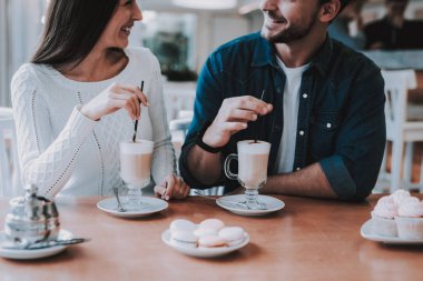 Cafe dinlenme çift. İki güzel genç erkek ve kadın var. Kişi masada oturuyor. Mutlu ve gülen kişidir. İnsanlar içme kahve ve bir kek yeme. Güneşli gün.