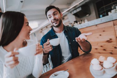 Cafe dinlenme çift. İki güzel genç erkek ve kadın var. Çift bir çay içiyor. Kadınla konuşan adam. Kişi masada oturuyor. Mutlu ve gülen kişidir. Güneşli gün.