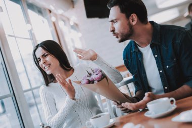 Kaç Cafe içinde. İki güzel genç erkek ve kadın var. Adam kadına, bir buket çiçek tutuyor. Kadın istiyorum Dont dinleme bir adam kişilerin masada oturuyor. İnsanlar üzgün.