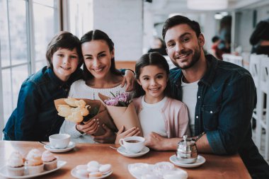 Aile Cafe bir tatil kutluyor. Anne, Baba, kızı ve oğlu ailedir. Anne ve Dauther bir çiçek buketleri Holding. Mutlu ve gülen kişidir. Aile portresi.