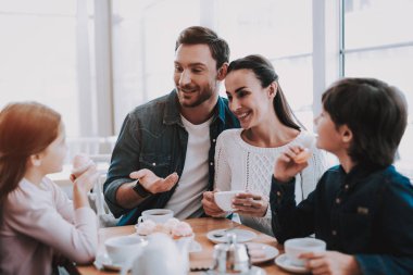 Cafe Resting ailedir. Anne, Baba, kızı ve oğlu ailedir. İnsanlar bir kek yeme ve bir çay içme. Kişi masada oturuyor. Mutlu ve gülen kişidir. Gündüz.