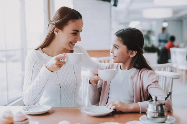 カップルは カフェで休憩です カップルは美しい若い母親と娘です カップからお茶を飲んでいます テーブルに座っています 人はお互いに見て 笑顔です — ストック写真