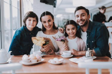 Aile Cafe bir tatil kutluyor. Anne, Baba, kızı ve oğlu ailedir. Anne ve Dauther bir çiçek buketleri Holding. Mutlu ve gülen kişidir. Aile portresi.