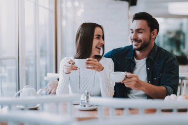 Cafe dinlenme çift. İki güzel genç erkek ve kadın var. Çift bir çay içiyor. İnsanlar birbirlerine arıyor. Kişi masada oturuyor. Mutlu ve gülen kişidir. Gündüz.