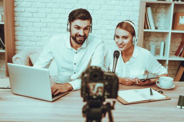 Blogcular bir Video yapar. Blogcular gülümseyen erkek ve kadın var. Kamera bir Video vuruyor. İnsanlar bir kulaklık takıyor. Mikrofon, Talking kişidir. Bir dizüstü bilgisayar kullanan adam. Studio iç insanlarda.