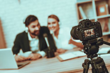 Bulanık görüntü blogcular bir Video yapar. Blogcular gülümseyen erkek ve kadın var. Video ile ilgili bir iş. Kamera bir Video vuruyor. İnsanlar giyen bir kulaklık mikrofon konuşuyor. Studio iç insanlarda.