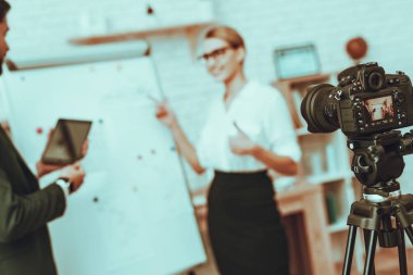 Bulanıklık görünümü blogcular bir Video yapar. Blogcular iş adamı ve iş kadını var. Video ile ilgili bir iş. Kamera bir Video vuruyor. Bir Tablet gösterilen adam. İş grafiği gösteren kadın. Studio iç.
