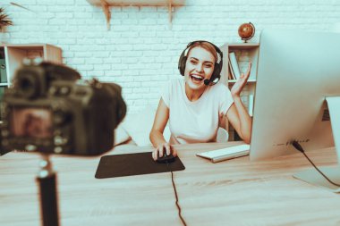 Blogger bir Video yapar. Blogger Gamer olduğunu. Blogger genç gülümseyen kadın var. Kamera bir Video vuruyor. Bilgisayarda bilgisayar oyunu oynamak kulaklık kadında. Kadın bir kameraya bakıyor. Studio iç.