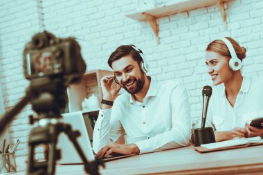 Blogcular bir Video yapar. Blogcular erkek ve kadın var. Kamera bir Video vuruyor. İnsanlar bir kulaklık takıyor. Kadın mikrofon konuşuyor. Bir dizüstü bilgisayar kullanan adam. Studio iç insanlarda.