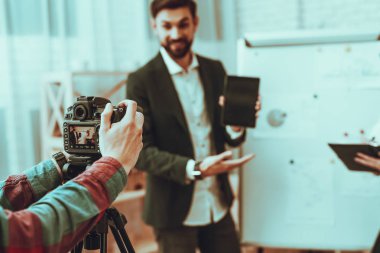 Bulanıklık blogcular bir Video yapar. Blogcular iş adamı ve iş kadını var. Video ile ilgili bir iş. Operatör bir Video kameraya ateş eder. Bir Tablet gösterilen adam. Kadın yazma not defterinde. Studio iç.