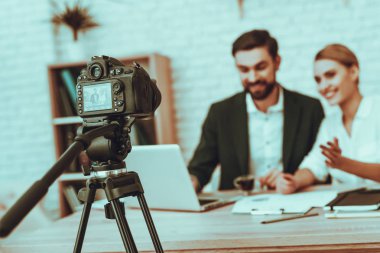 Blogcular yapar bir Video var. Blogcular genç gülümseyen erkek ve kadın var. Video ile ilgili bir iş. Kamera bir Video vuruyor. Becerikli alet ve malzemeleri masada. Studio iç insanlar. Görüntü bulanıklığı.