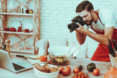 Fotoğrafçı bir fotoğraf yapar. Fotoğrafçı Genç sakallı adam adam alarak resim, yemek bir yemek değil. Adam bir fotoğraf makinesi kullanıyor. Laptop ve farklı yemek masada. Studio iç adam.